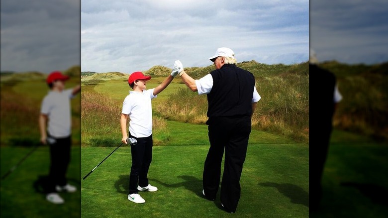 Young Barron Trump high-fiving Donald on golf course
