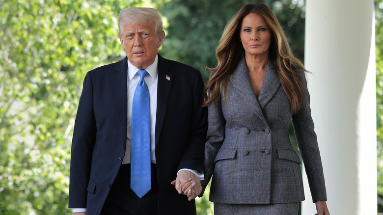 Donald and Melania Trump walking hand in hand looking serioius