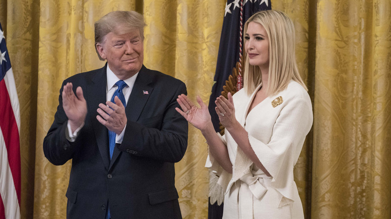 Donald and Ivanka Trump applauding in front of gold curtains