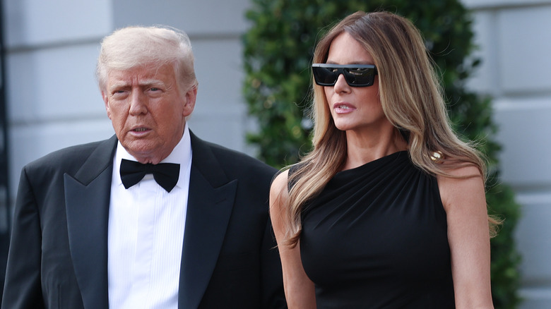 Donald Trump in a bowtie and suit leaving the White House with Melania Trump who's wearing a black dress and sunglasses.