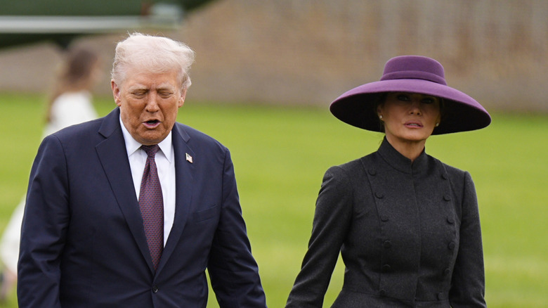 Melania and Donald Trump walking next to each other while holding hands