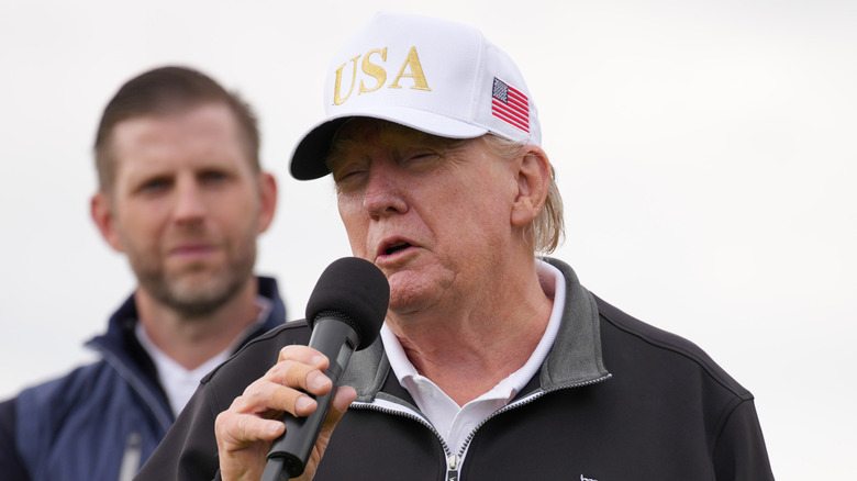 Eric Trump watching Donald Trump speak into a microphone