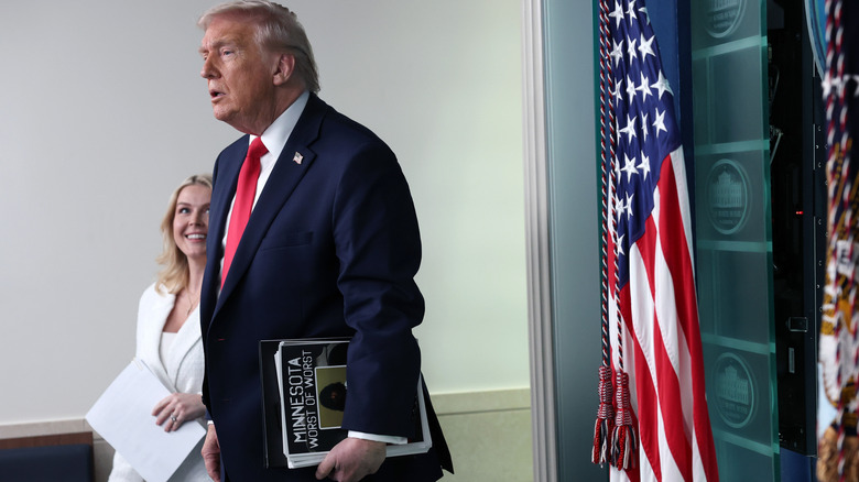 Karoline Leavitt smiling Donald Trump with packet in WH briefing room