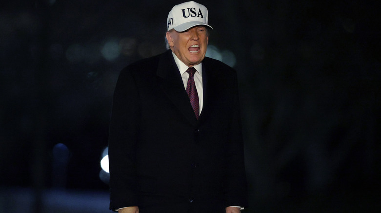 Donald Trump seemingly yelling at someone out of the shot in a white USA hat
