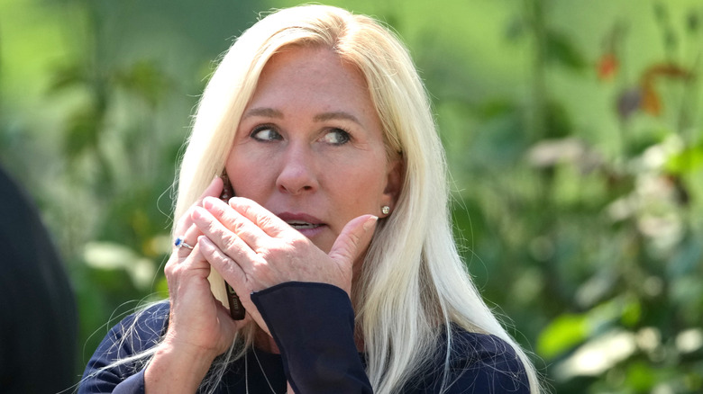 Marjorie Taylor Greene covering her mouth speaking into her phone
