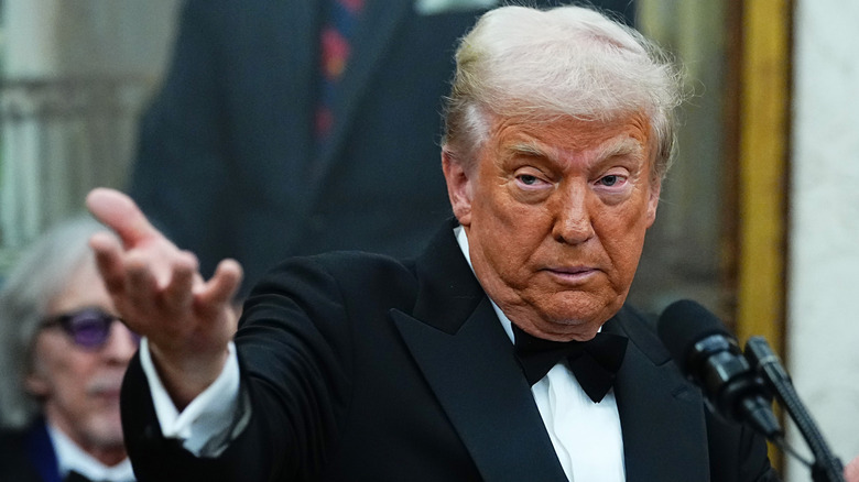 Donald Trump at podium in tuxedo hand outstretched