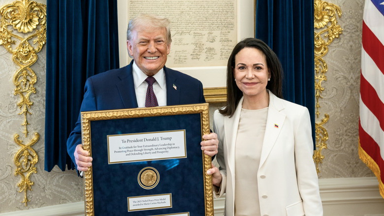 Donald Trump holding a framed Nobel Peace Prize medal while standing next to María Corina Machado