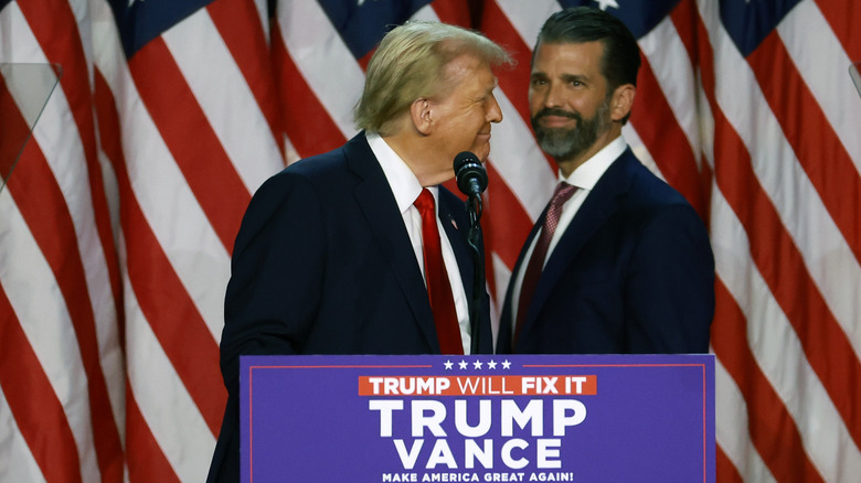 Donald Trump delivering a speech while Donald Trump Jr. looks on