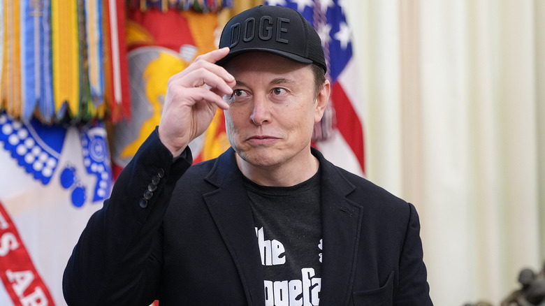 Elon Musk touching his DOGE hat in the Oval Office