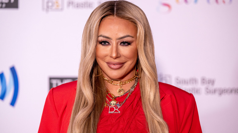Aubrey O'Day smiling at an event in a red dress