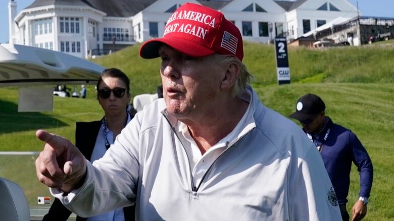 Donald Trump points at someone while on a golf course in 2023