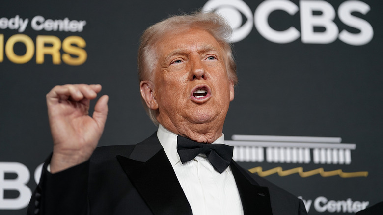Donald Trump speaking while gesturing with his hand in a tuxedo