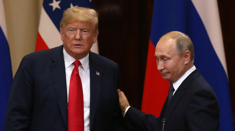 Russian President Vladmir Putin standing with hand on Donald Trump's arm
