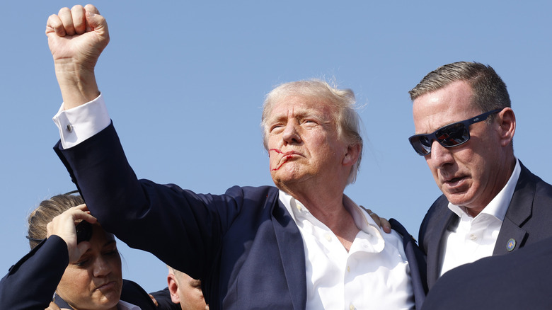 Donald Trump raising his fist, blood on his face, with Secret Service agents