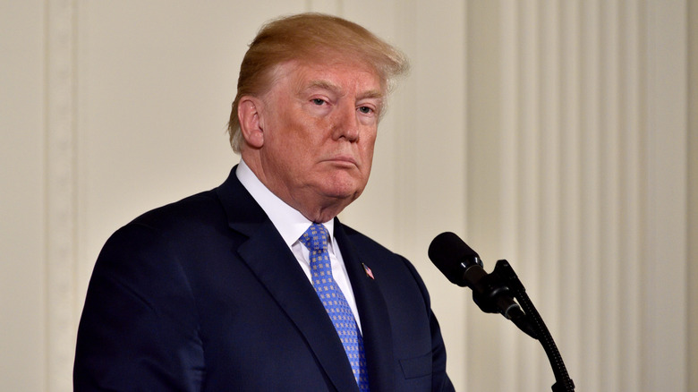 Former President Donald Trump standing behind a microphone