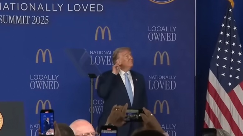 Donald Trump holding his hand to his ear before his speech at the McDonald's Impact Summit