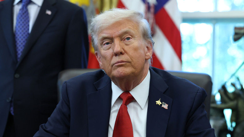 Donald Trump sits at his desk