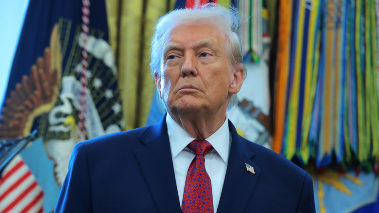 Donald Trump looking grumpy in a navy suit and a red tie