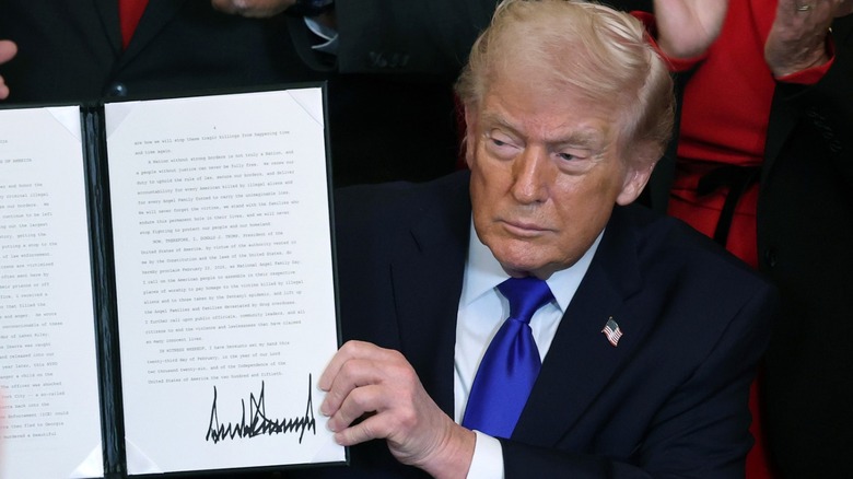 Donald Trump holds up a proclamation with his signature in the East Room at the White House in Washington, DC (2026)