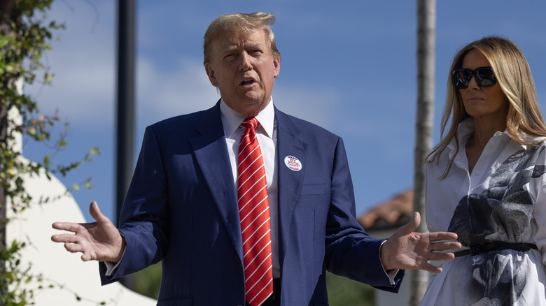 Donald Trump hands spread Melania in background