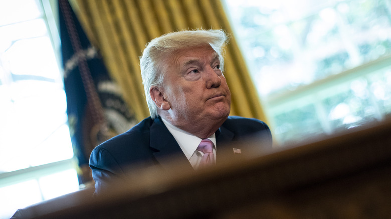 Donald Trump sitting behind the Resolute Desk in the White House