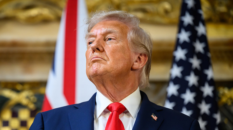 Donald Trump looking haughty while lifting his chin in a navy suit with a red tie