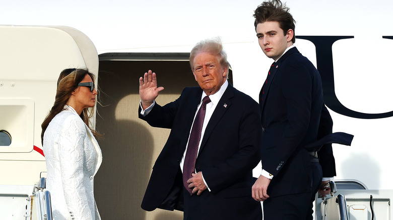Donald Trump waving as he boards a plane with Melania Trump and Barron Trump