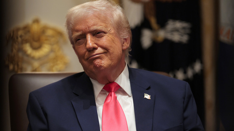 Donald Trump makin a face in a pink tie and a blue suit