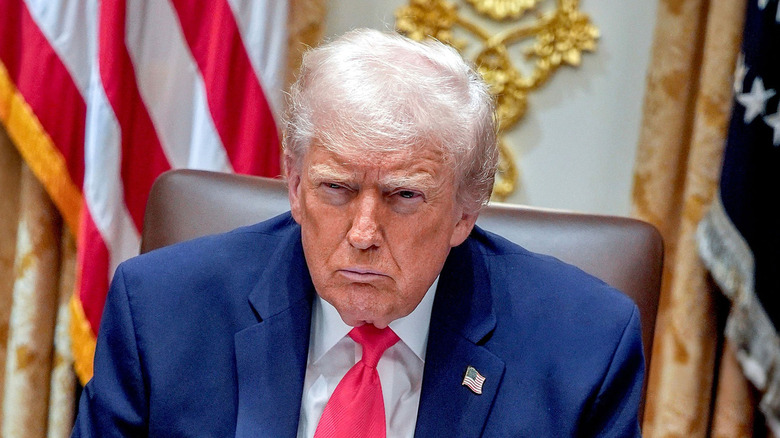 Donald Trump looking angry in front of American flags