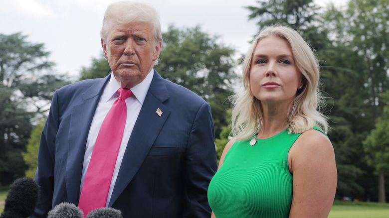Karoline Leavitt looking determined as she stands next to Donald Trump in a green dress