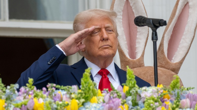 Donald Trump saluting in front of flowers