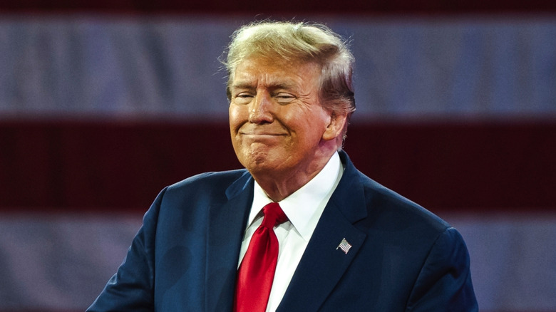 Donald Trump smiling while standing at a podium during a political event