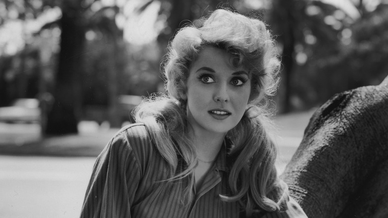 Donna Douglas leaning on a tree and looking thoughtful