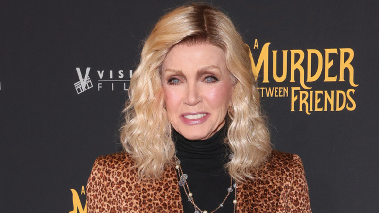 Donna Mills smiling while posing at an event in a leopard print jacket