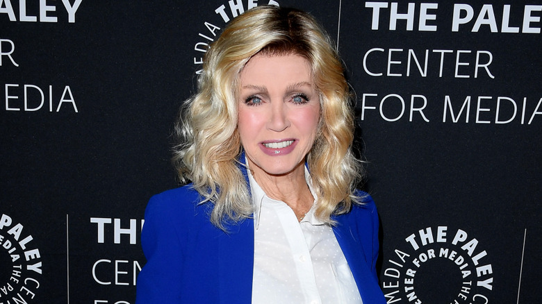 Donna Mills smiling while posing at an event in a blue blazer