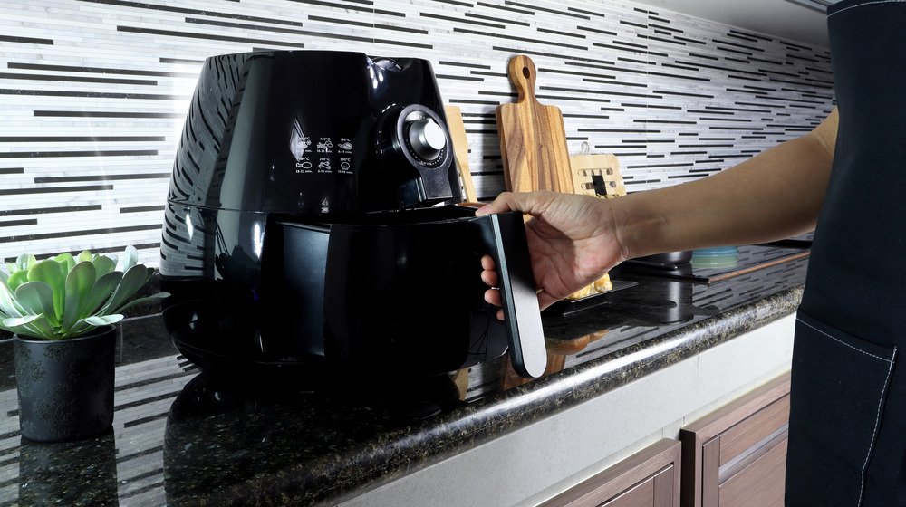 Hand on air fryer tray