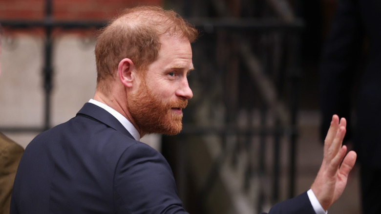 Prince Harry waving to onlookers while walking in the streets