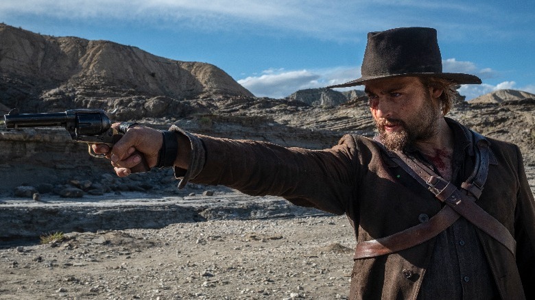 Douglas Booth holding a gun
