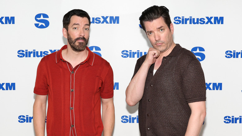 Drew and Jonathan Scott posing for a photo against a Sirius XM background in 2025