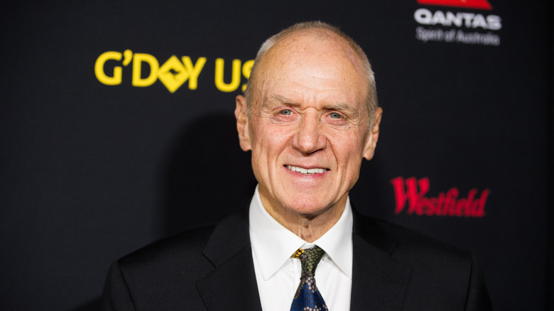 Alan Dale smiling in black formals