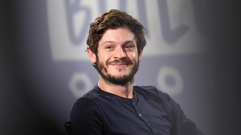 Iwan Rheon smiling in a blue button-up t-shirt