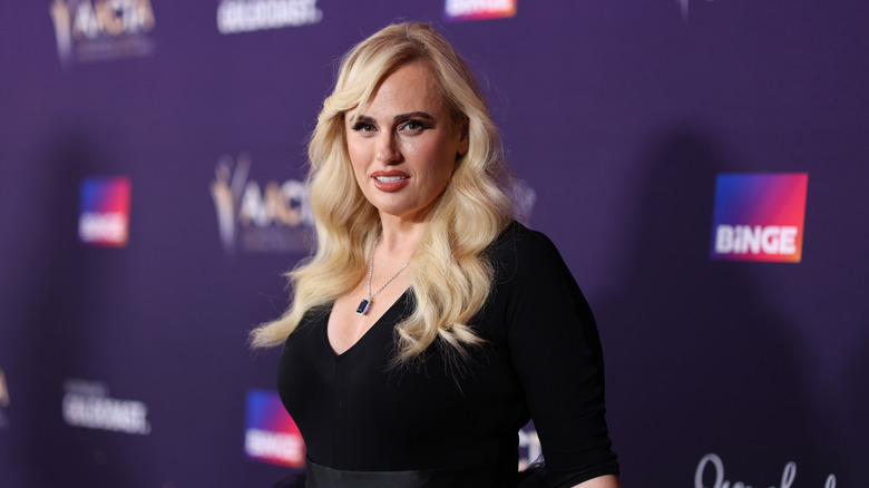 Rebel Wilson in a figure-hugging black dress and solitaire necklace