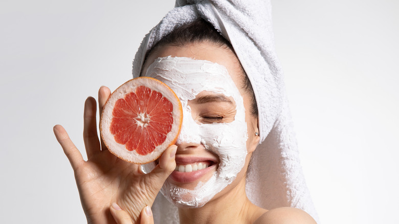 Woman wearing facemask holding a grapefruit 