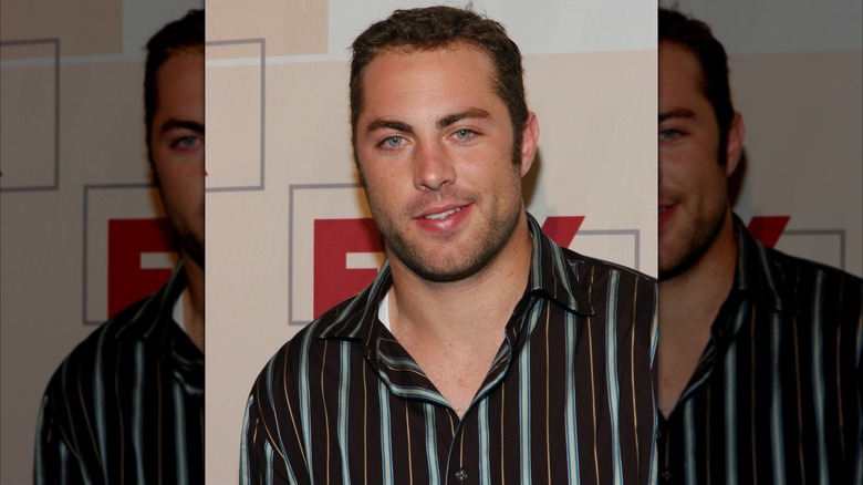 A young Jay McGraw smiling and wearing a striped button up shirt in 2004