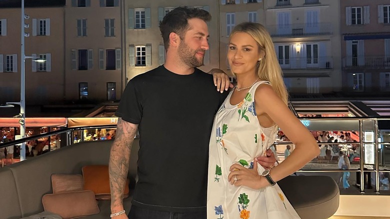 Dr. Phil's son Jordan looks at his wife with his arm around her while she smiles at the camera on a boat.