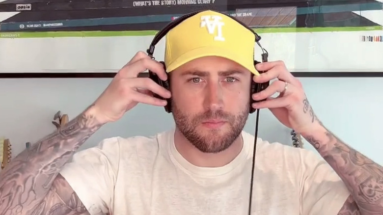 Dr. Phil's son Jordan sits wearing a yellow hat putting headphones on looking into the camera