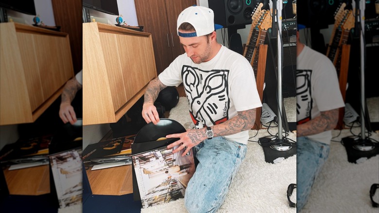 Dr. Phil's son Jordan McGraw sits on the ground flipping through records with guitars behind him.