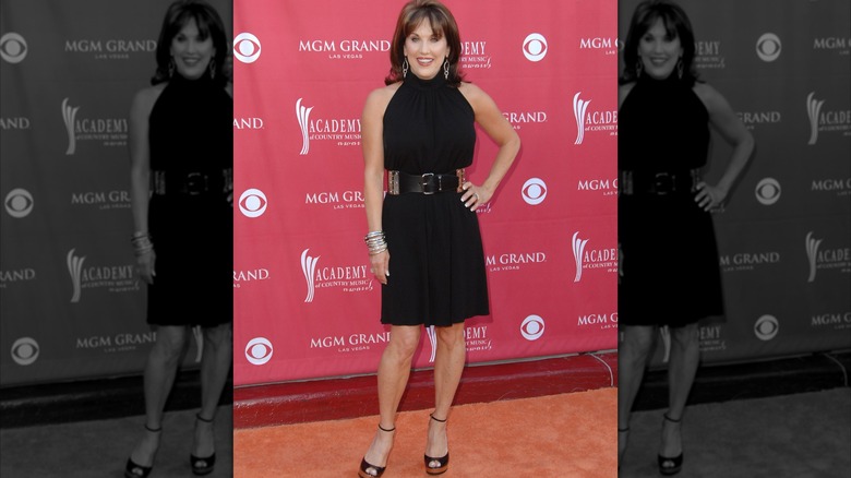 Robin McGraw smiling and posing with hand on hip in a black dress