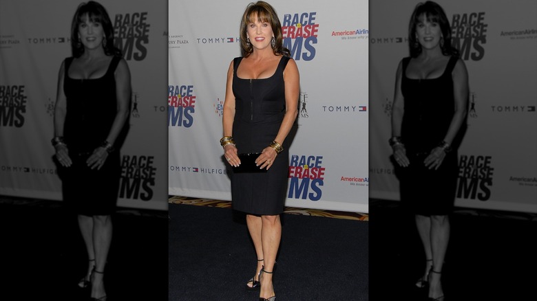 Robin McGraw smiling while holding handbag with both hands