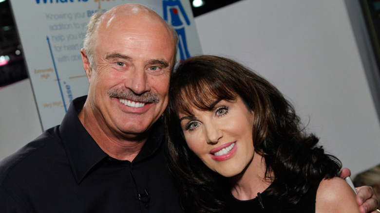 Smiling Robin McGraw leaning on Dr. Phil.
